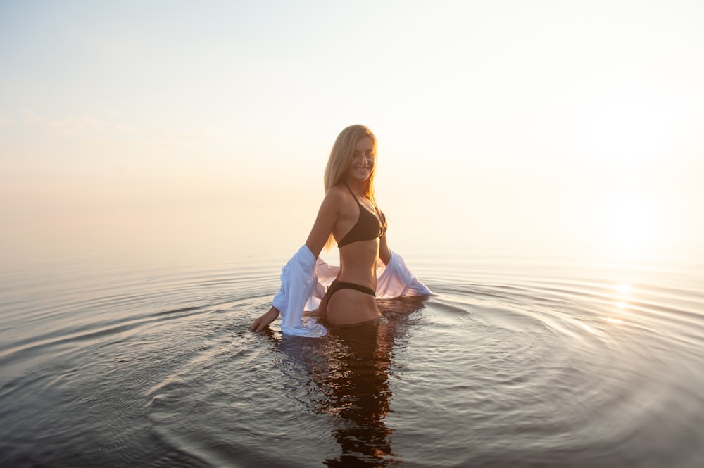 mulher usando biquíni preto definido em pé no meio do corpo de água