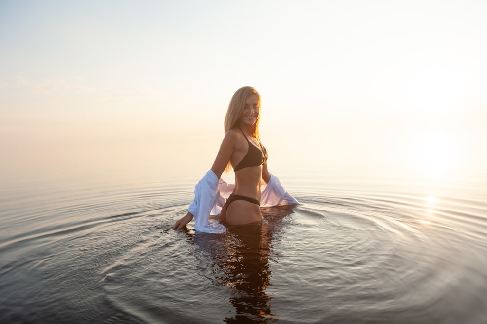 donna che indossa bikini nero set in piedi nel mezzo dello specchio d'acqua