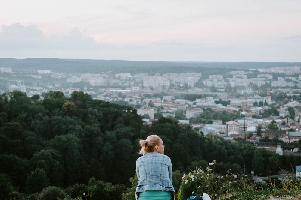 woman sitting overlooking city buildings during daytime