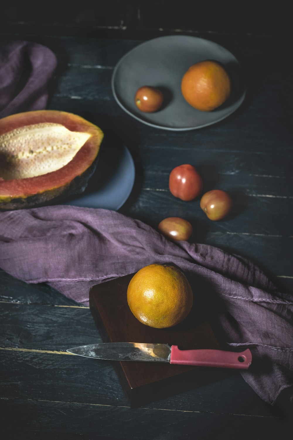 Früchte in der Nähe von rotem und grauem Messer auf Holz