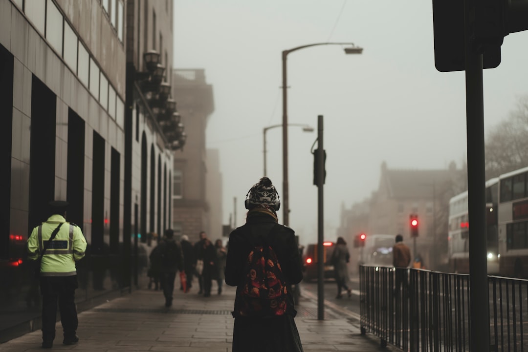 person wear black coat and backpack walking on sidewalk