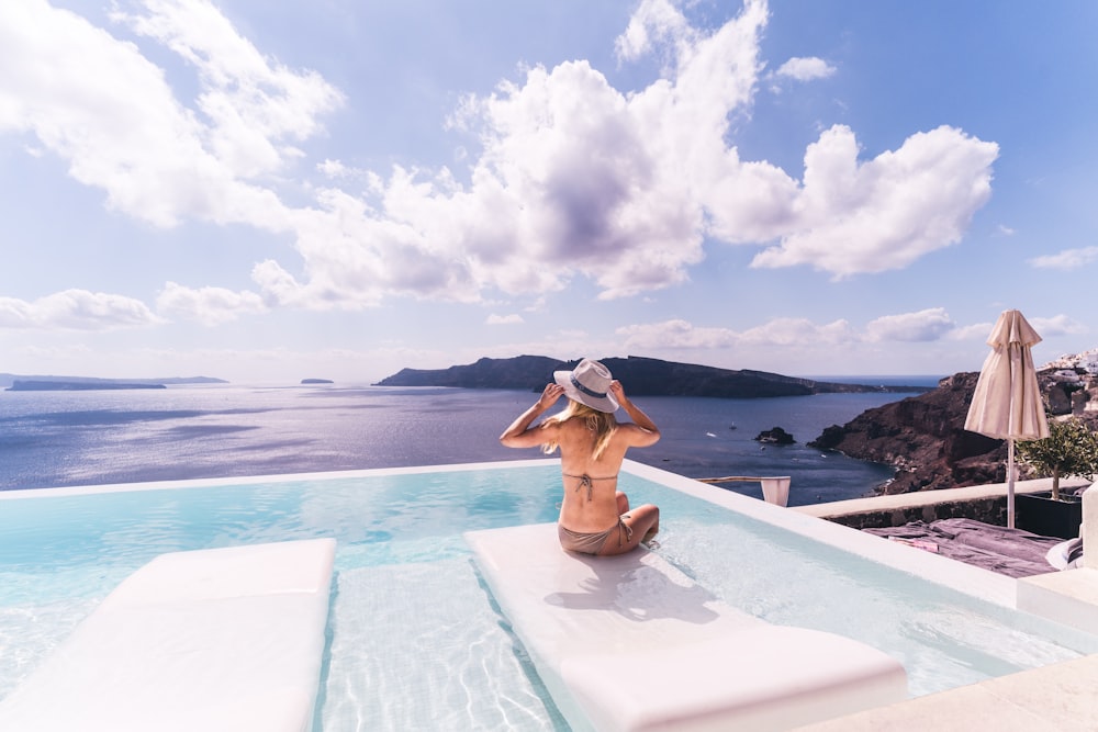 woman sitting on white chair near body of water during daytime