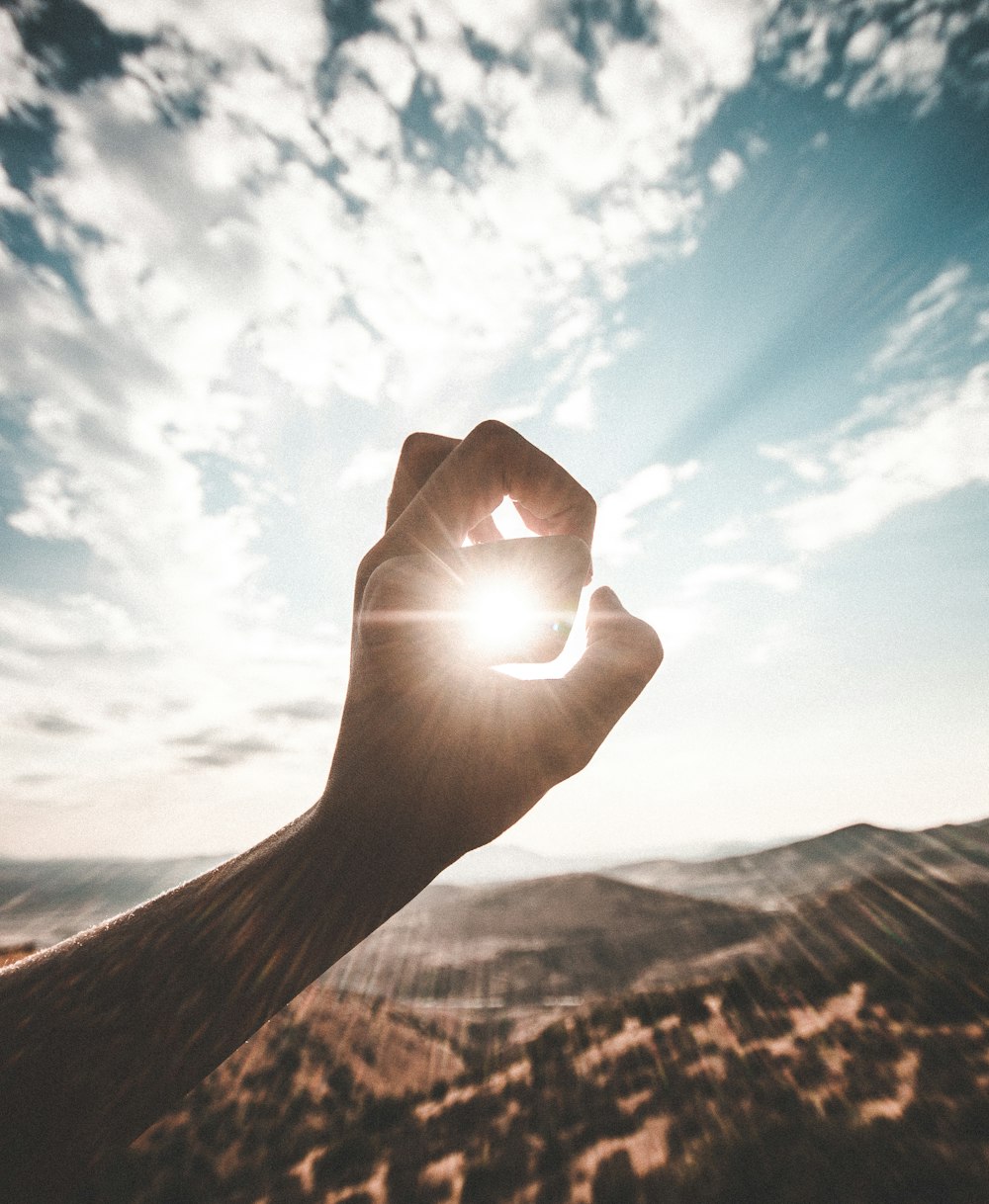 Photographie de soleil éblouissant à travers le trou du doigt