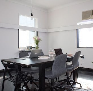 rectangular brown wooden table with six chairs and silver MacBook on top