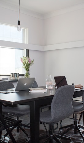 rectangular brown wooden table with six chairs and silver MacBook on top