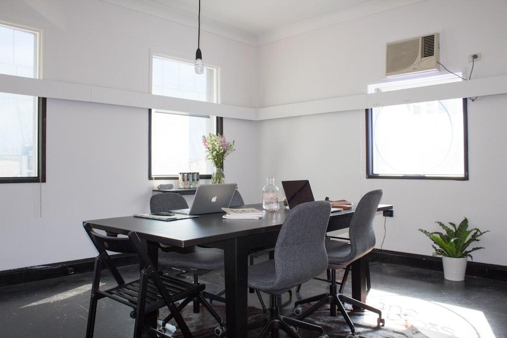 rectangular brown wooden table with six chairs and silver MacBook on top