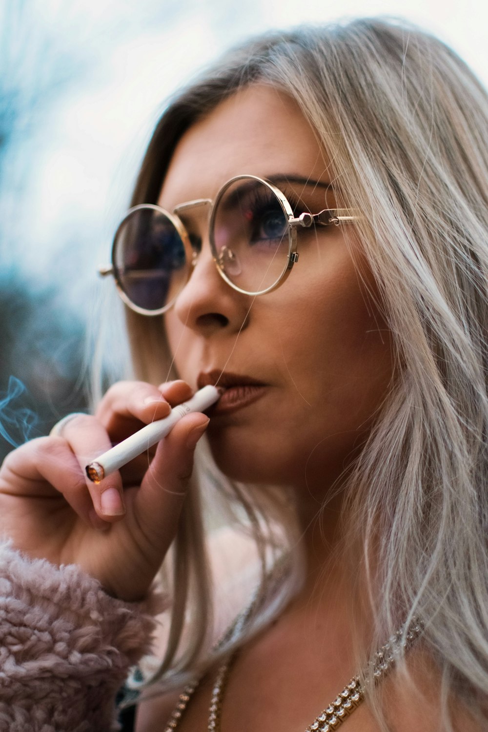 Persona sosteniendo un palo de cigarrillo con anteojos