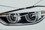 A close-up view of a sleek car headlight with a modern design. The headlight features intricate detailing and reflective surfaces, highlighting its precision engineering.