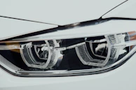 A detailed view of a car’s blue-tinted headlight and grille, showcasing precision design.