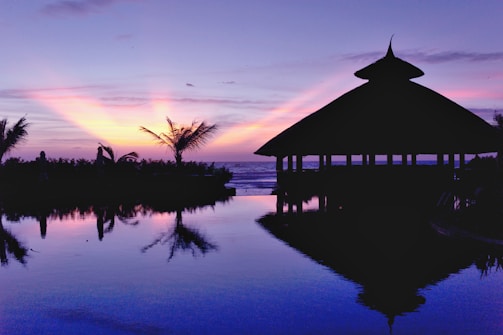 A serene view of the backwaters at sunset with cottages nestled along the shore at Aqua Terra Villas.