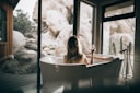 woman in white bathtub holding clear drinking glass