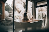woman in white bathtub holding clear drinking glass