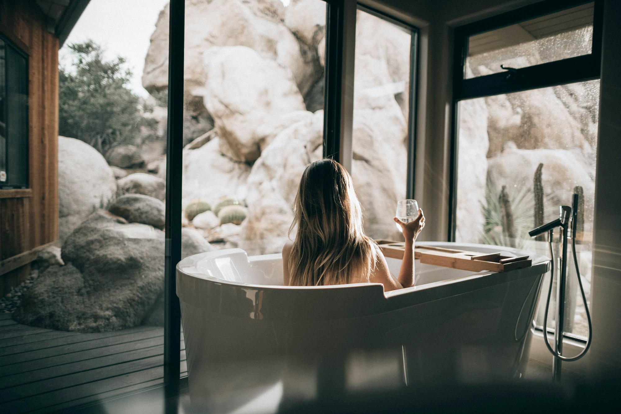 Woman in bath with a glass of wine practicing self-care