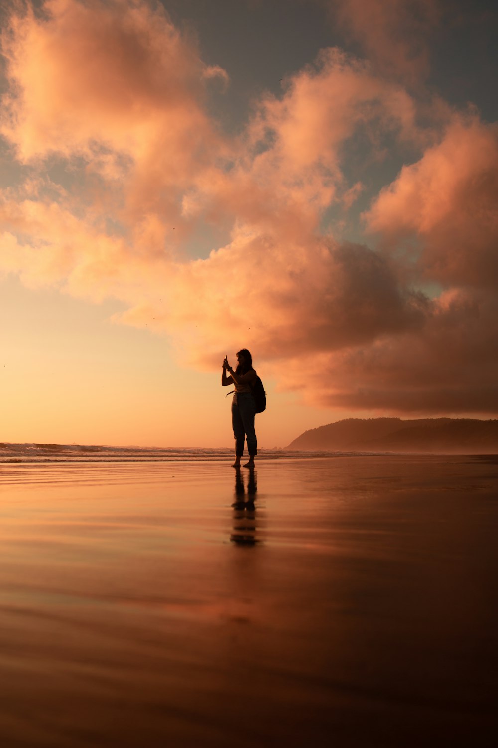 silhouette of woman standing on seashore in golden hour background
