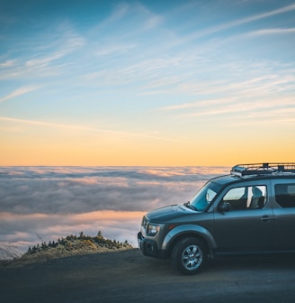 grey SUV beside sea of cloud