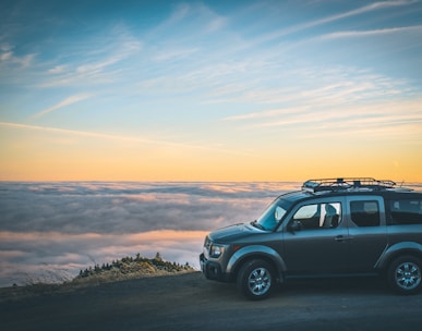 grey SUV beside sea of cloud