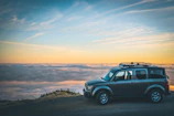 grey SUV beside sea of cloud