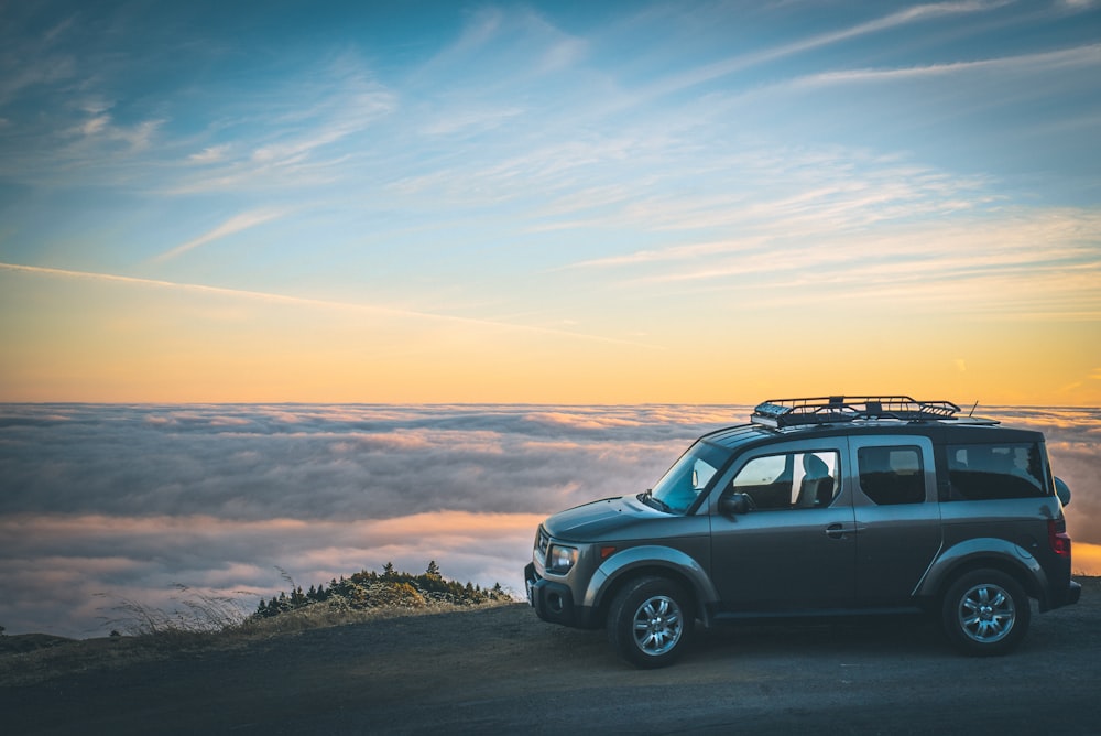 grauer SUV neben Wolkenmeer