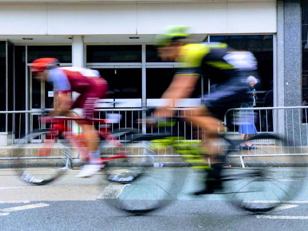 two men riding on black and red road bikes on gray concrete pavement during daytime