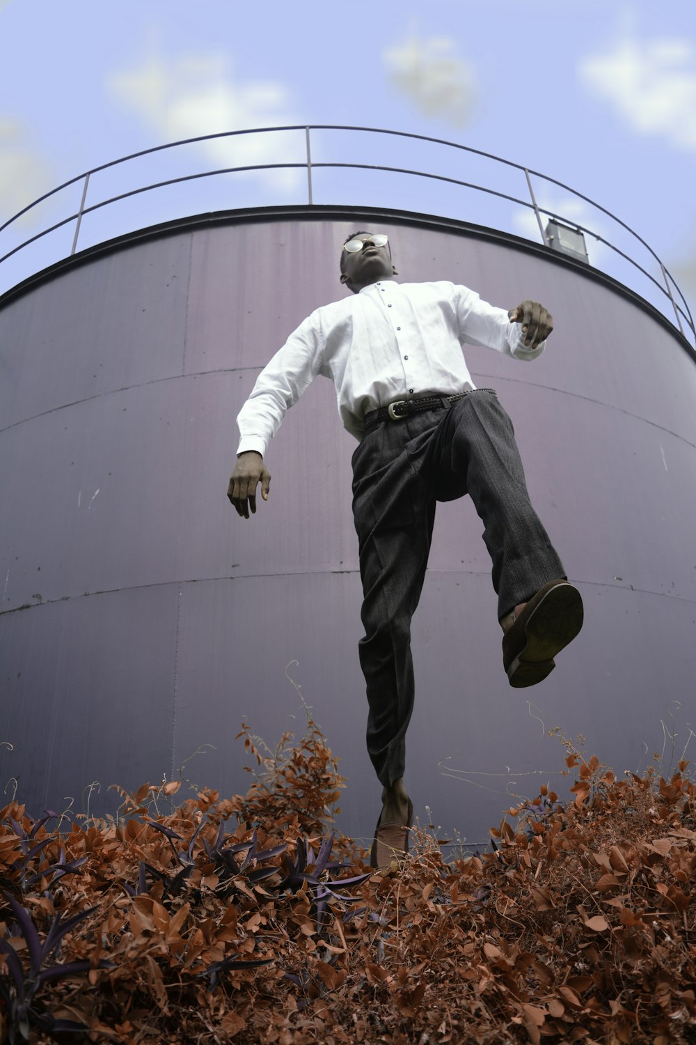 man in white dress shirt jumping over the plant