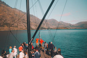 Group of friends enjoying a boat tour on a crystal-clear glacier lake under bright blue skies.