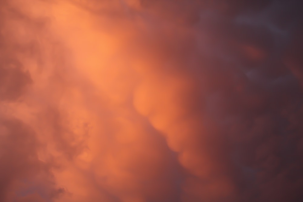 a plane flying through a cloudy sky at sunset