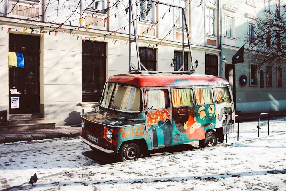 red and teal van parked beside white building