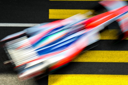 A dynamic racing car speeding on a track with a blurred background.