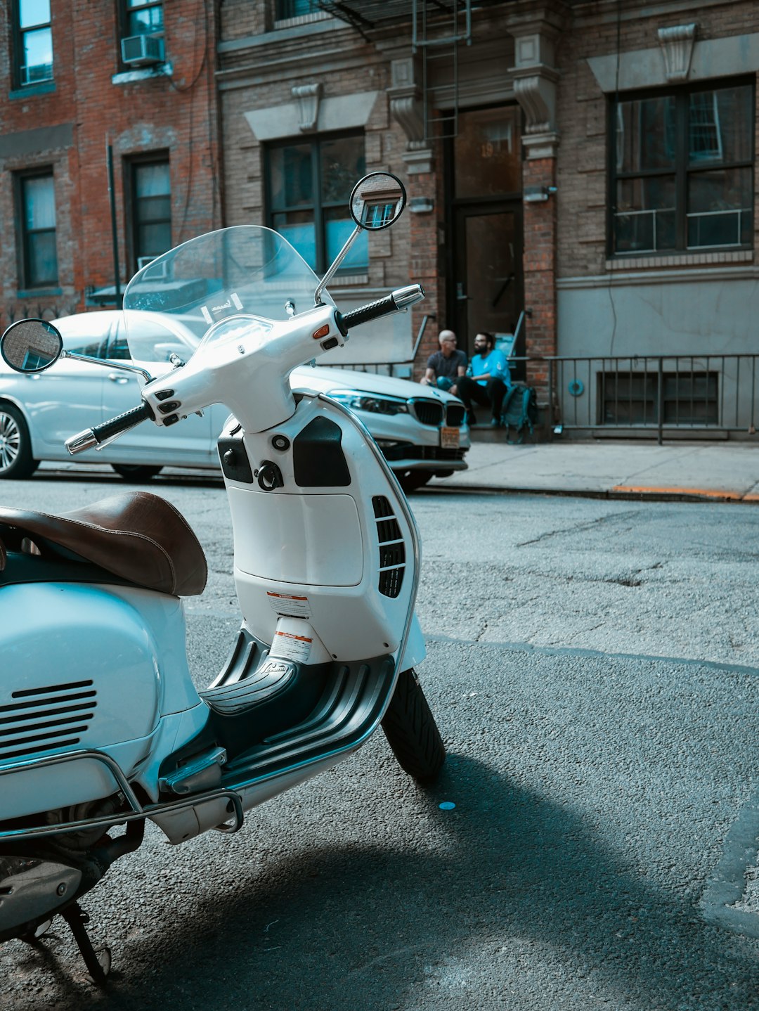 gray motor scooter parked near car