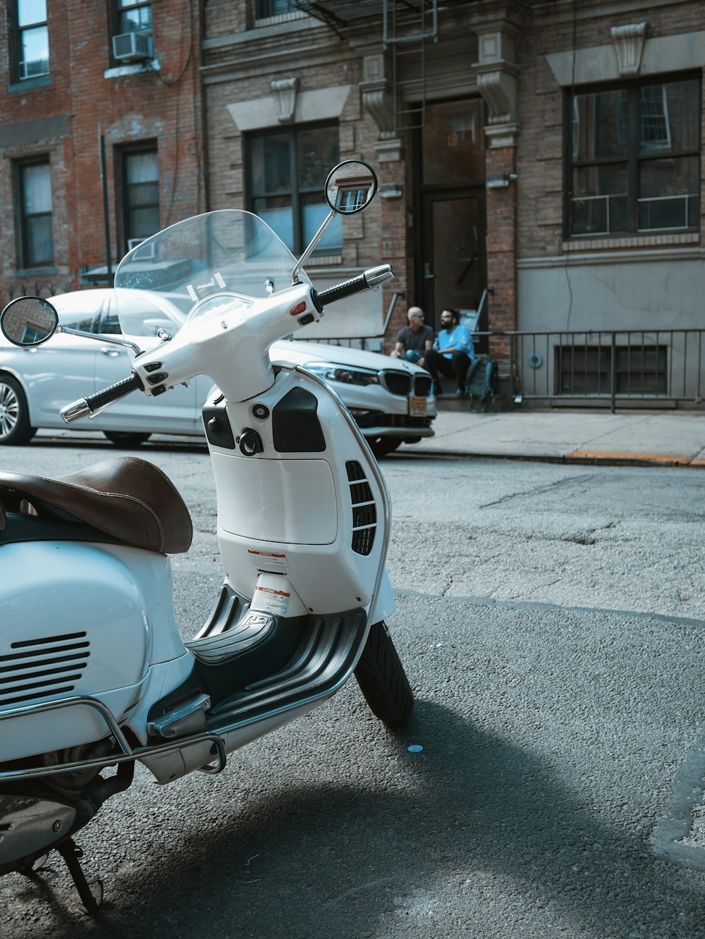 gray motor scooter parked near car