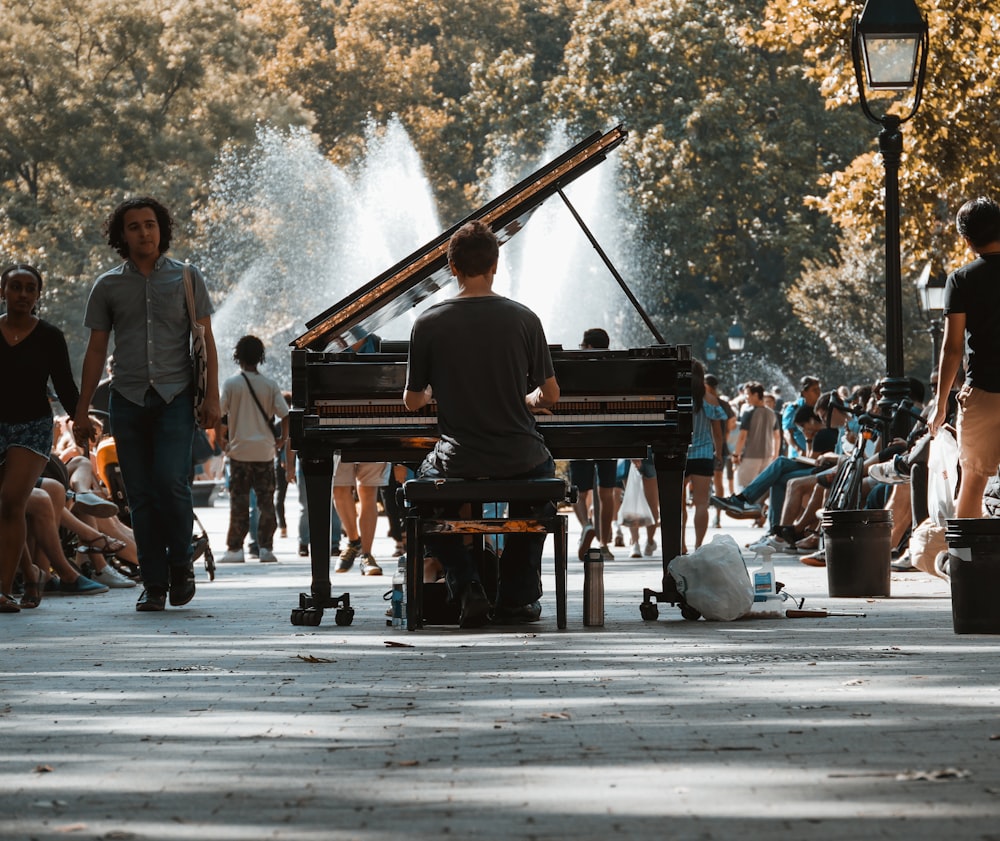 Fotografia a fuoco selettiva dell'uomo che suona il pianoforte a coda tra la folla