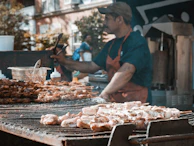 A street vendor’s hand holding a perfectly grilled skewer of meat, with city lights blurred behind.