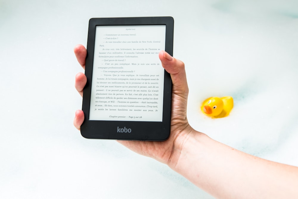 Person, die den Amazon Kindle E-Book-Reader eingeschaltet hält