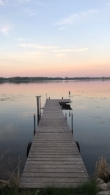 A technician installing a wooden dock by a calm lake shore at sunset.