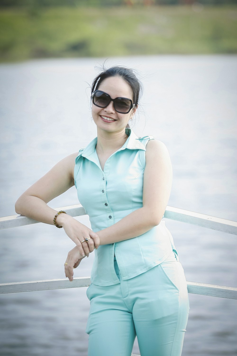 smiling woman wearing collared shirt leaning on white railing