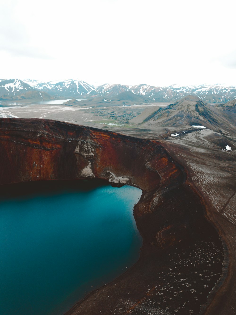 body of water near mountain in distant of snow capped mountain