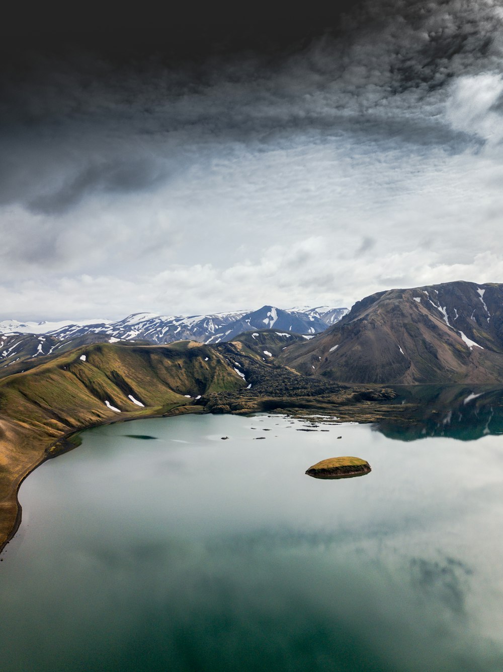 white clouds over body of water and green mountains