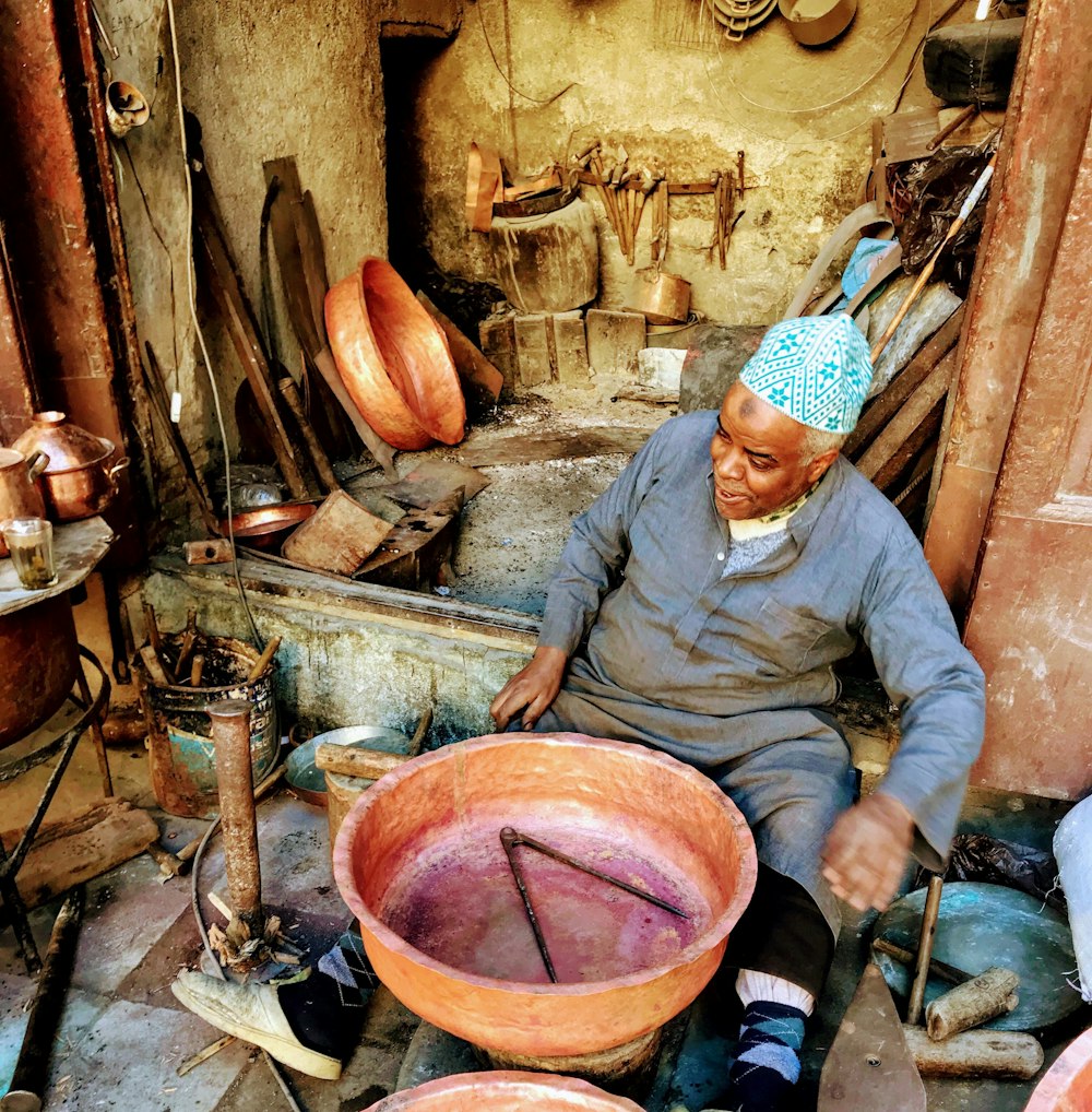 a man sitting in a room filled with pots and pans