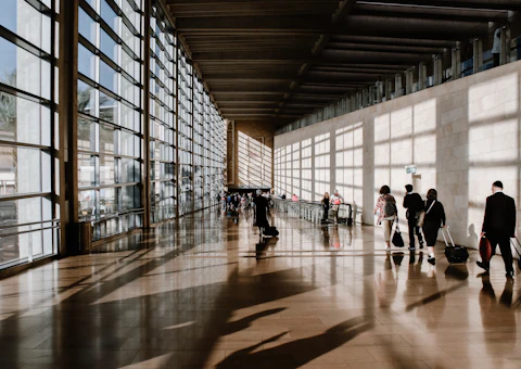 Grand hall d'aéroport lumineux avec voyageurs, illustrant l'arrivée à l'aéroport Mohammed V de Casablanca avant le trajet vers Rabat