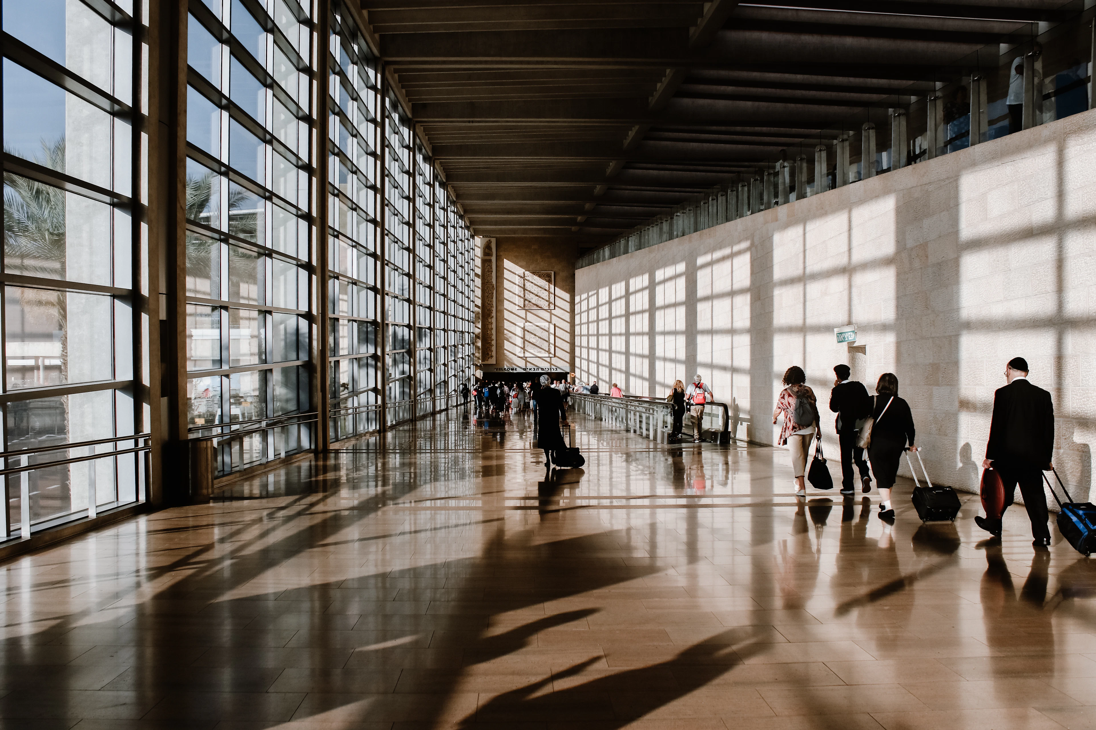 Sunlit airport terminal with travellers and long shadows