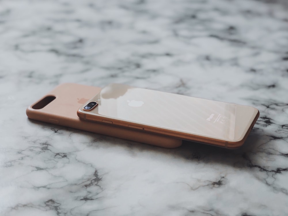dois iPhones dourados na superfície marrom