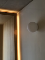 A minimalist interior with a clean, modern design. Soft lighting creates a warm ambiance along the wooden paneling. The neutral tones of the walls and ceiling complement the subtle geometric features.