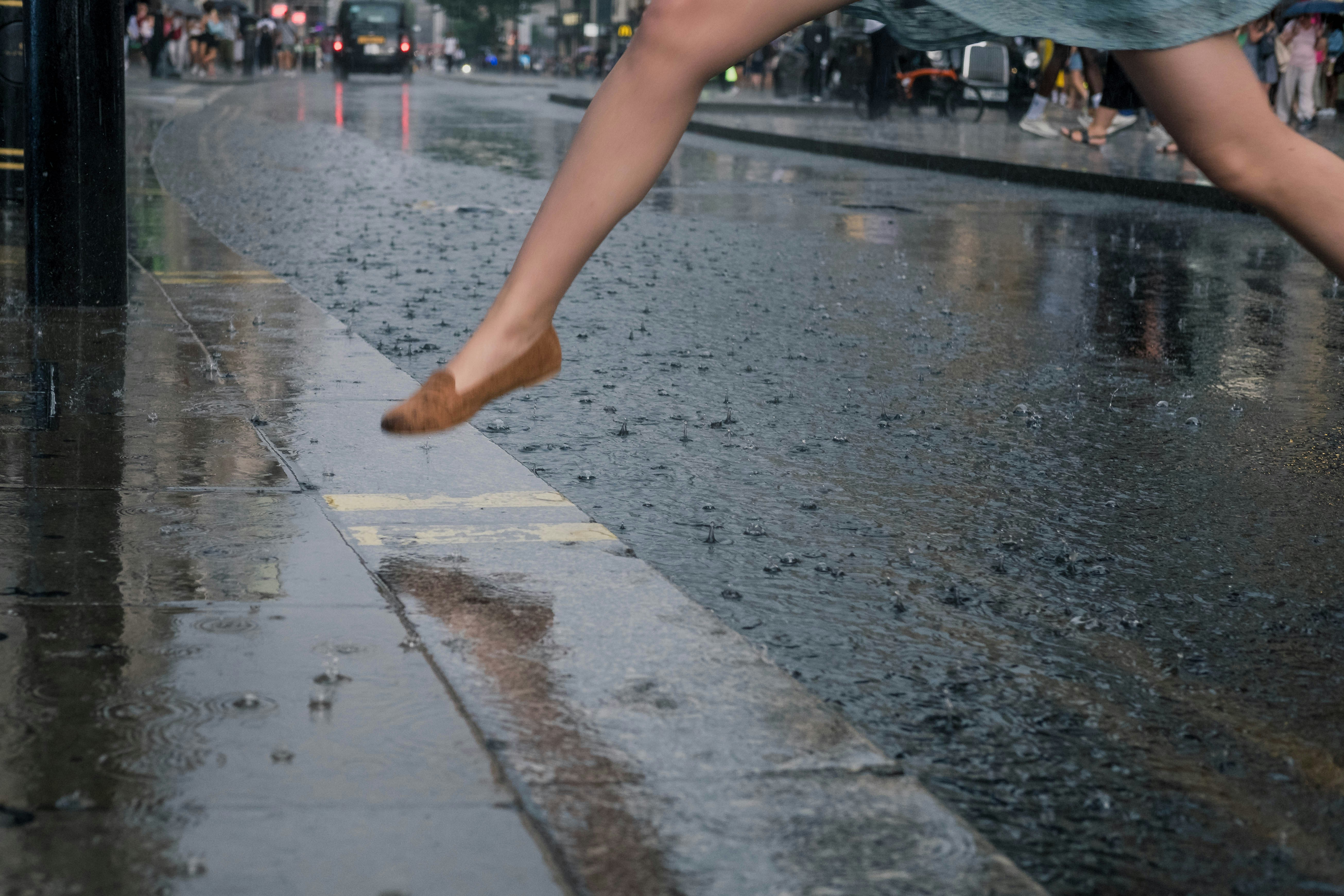 woman jumping on water near sidwalk