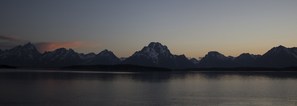 Silhouettenfotografie eines Berges in der Nähe eines Gewässers