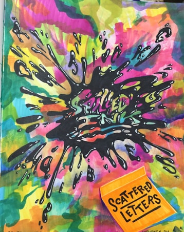 A vibrant, abstract artwork featuring a colorful explosion of splattered paint. The center has black ink splashes with the text 'SPILLED INK' partly visible. A bright orange sticky note in the bottom right corner has 'SCATTERED LETTERS' written on it.