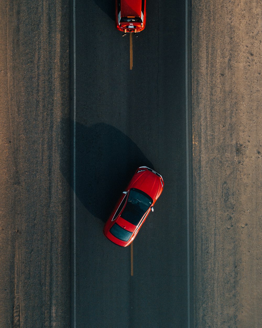 two red vehicles on road during daytime