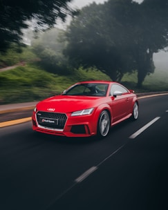 red Audi coupe on road near trees at daytime