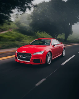 red Audi coupe on road near trees at daytime