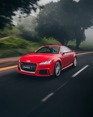 red Audi coupe on road near trees at daytime