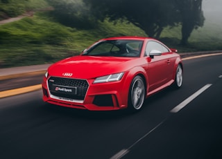 red Audi coupe on road near trees at daytime